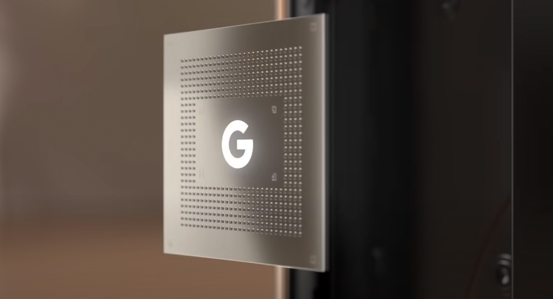 A rendering of the Google Tensor chip with the G logo, floating in front of a blurry background